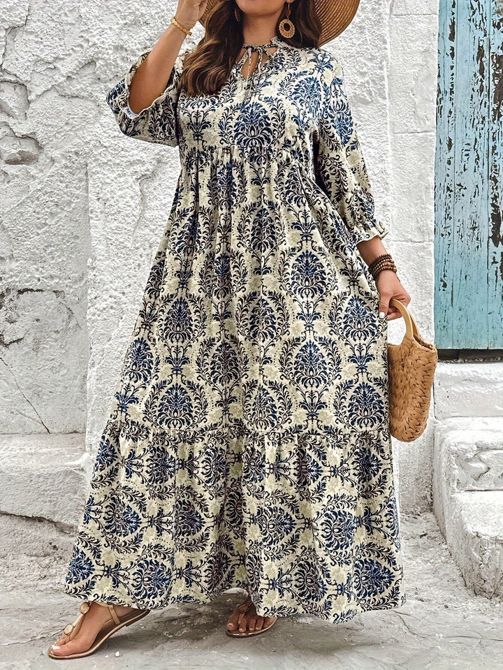 Woman strolling by the sea in the Harriet mosaic print maxi dress with a keyhole neckline and bow detail.