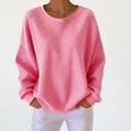 A woman wearing a relaxed-fit waffle-stitch jumper in soft pink with a textured surface
