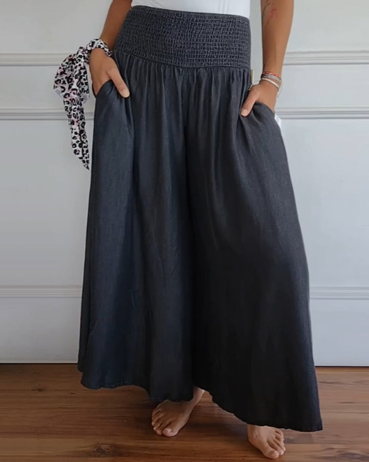 Woman wearing high-waist wide-leg trousers with a tucked-in blouse, mid-stride.