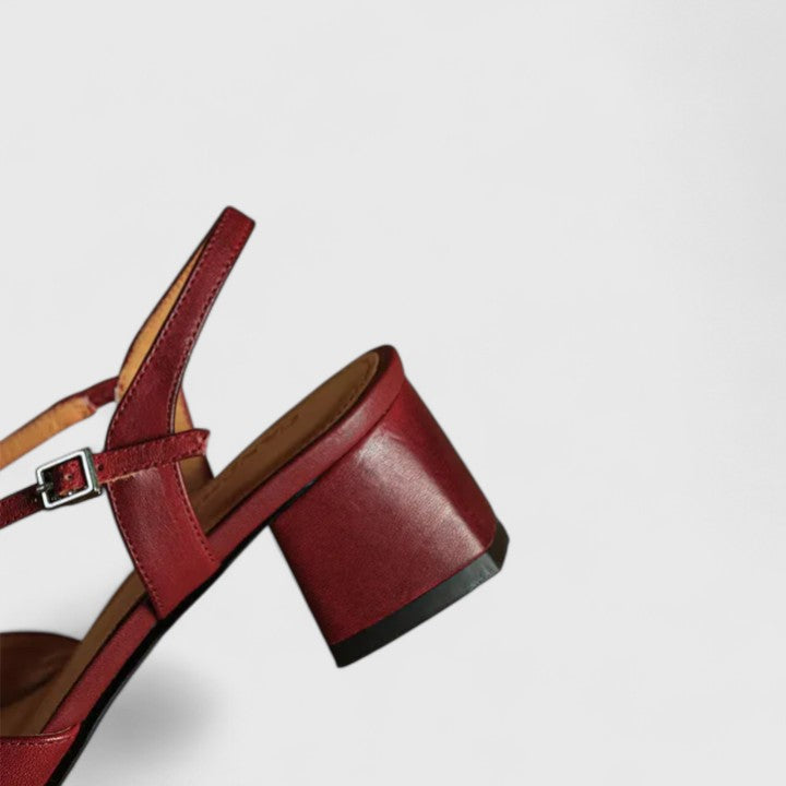 A woman wearing beige chic block heel sandals with an adjustable strap at an evening event.