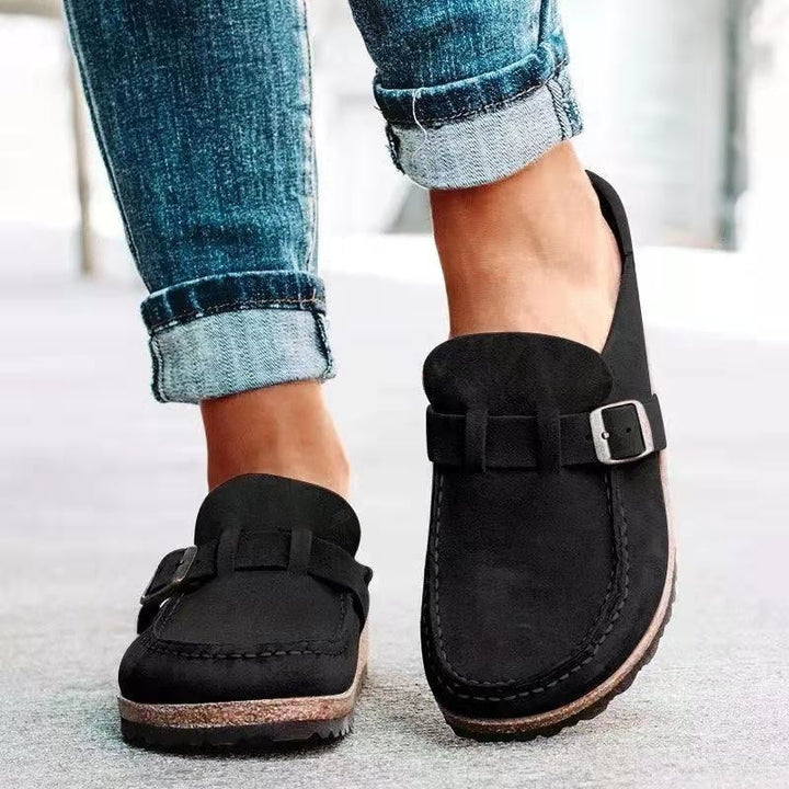 A woman wearing soft green bow loafers with cropped jeans on a city stroll.