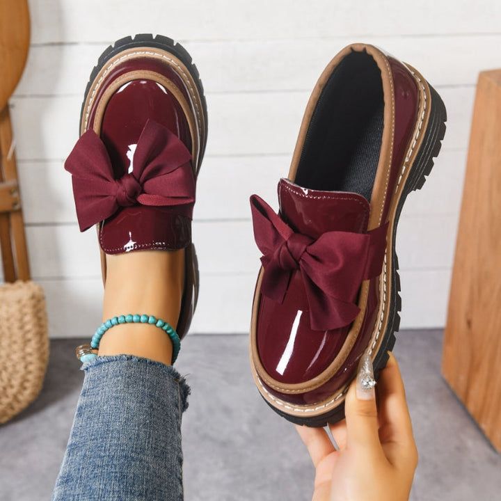 Bold loafers with a high-shine finish and statement bow detail, available in green, beige, black, brown and burgundy