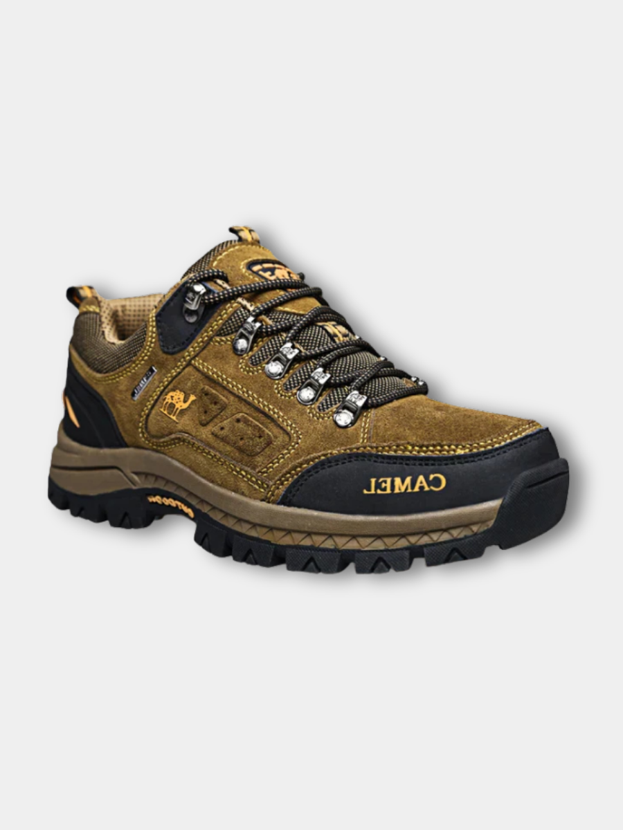 Men's khaki outdoor hiking boot with a rugged sole and lace-up front on a trail setting