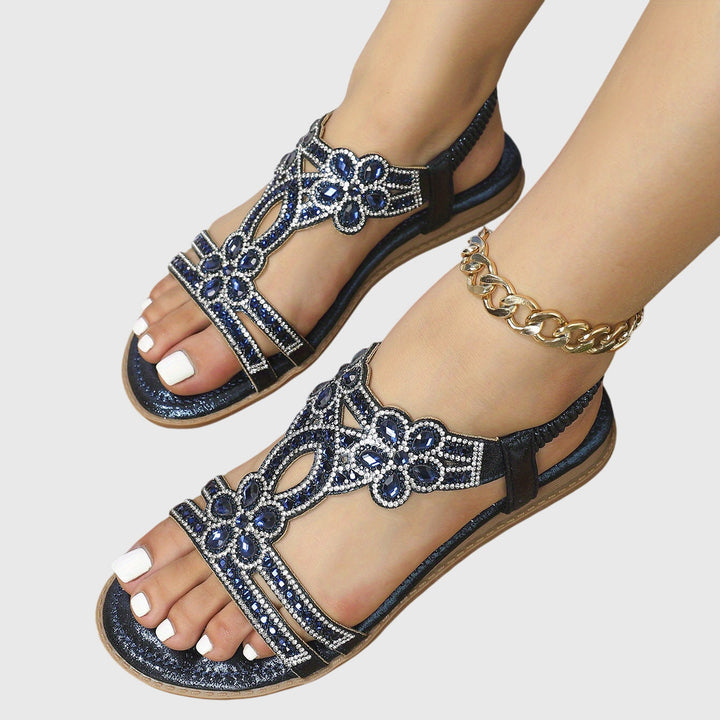 A woman wearing elegant gold open-front sandals with supportive straps and a cushioned sole.