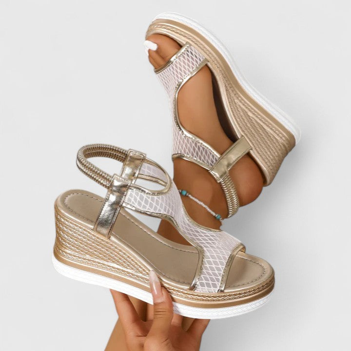 A woman wearing beige chic sandals with a cushioned sole and adjustable strap.