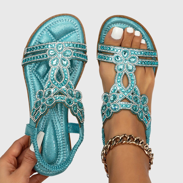 A woman wearing elegant gold open-front sandals with supportive straps and a cushioned sole.