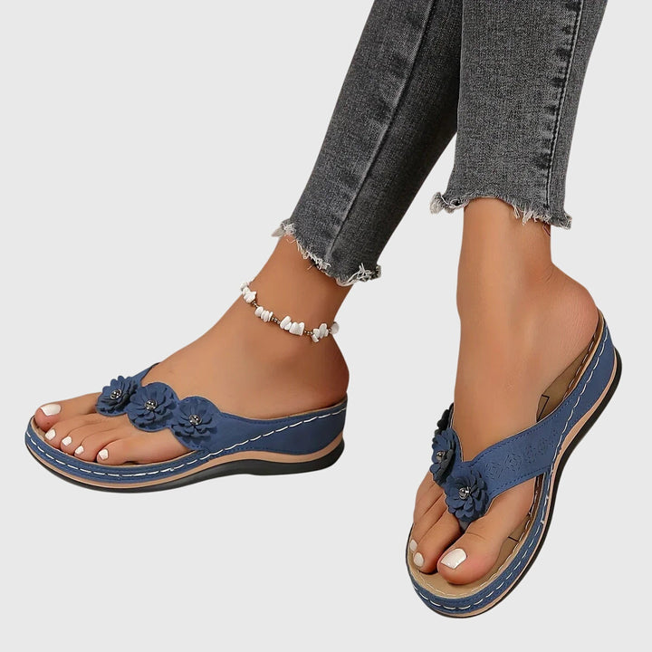 A woman wearing navy cushioned flip-flops with a supportive insole and open-front design.