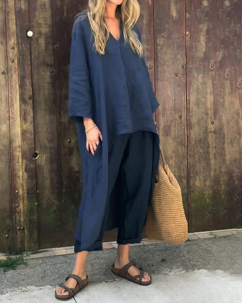A woman wearing a blue asymmetric tunic with wide-leg trousers