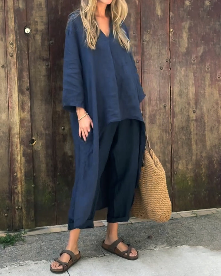 A woman wearing a blue asymmetric tunic with wide-leg trousers