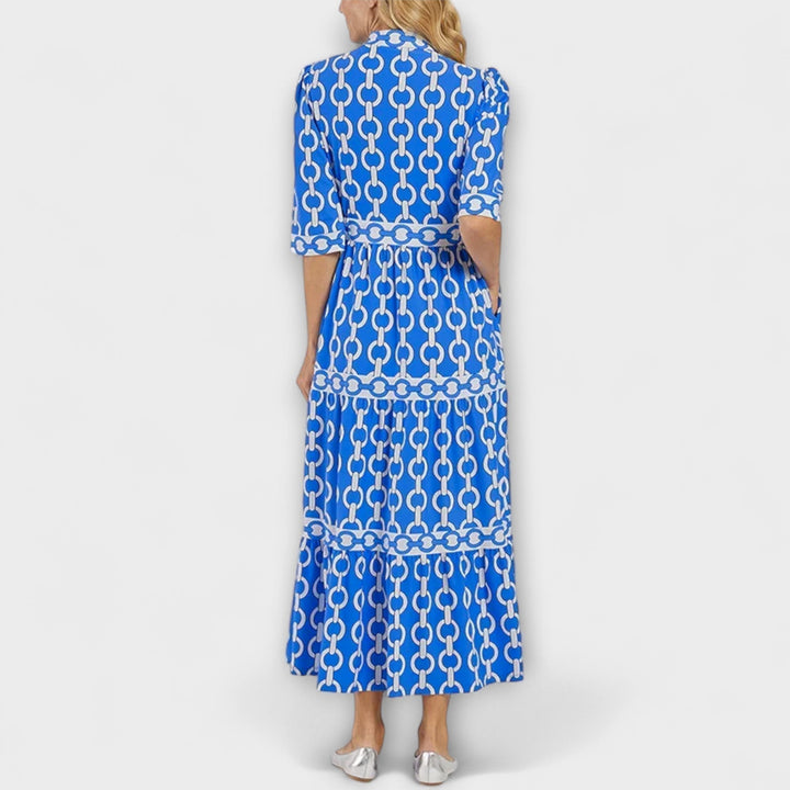 A woman wearing a flowing chain print midi dress that drapes elegantly as she walks.
