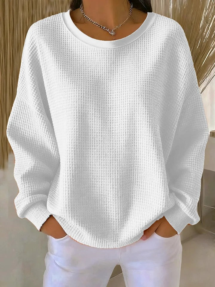 A woman wearing a relaxed-fit waffle-stitch jumper in soft pink with a textured surface
