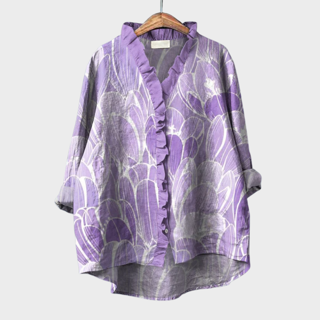 A woman wearing a light violet artful-print summer blouse over simple trousers