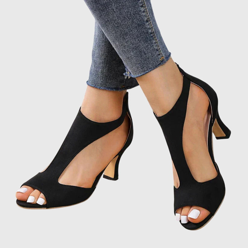 A woman wearing flexible orthopaedic heels, standing comfortably in a polished everyday outfit.