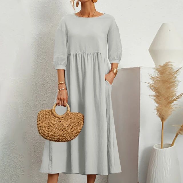A woman wearing the Sheila fitted waist midi dress with three-quarter sleeves and a flowing skirt.