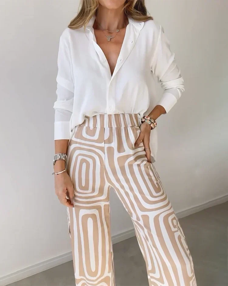 A woman wearing a plain button-up top with geometric-print trousers and a belt at the waist.