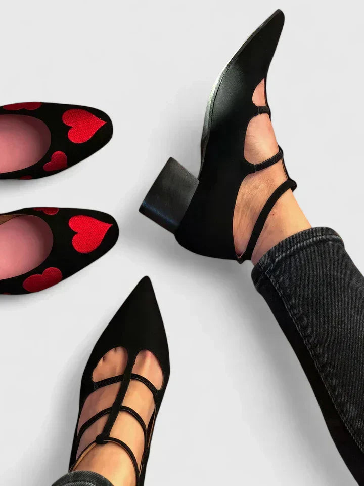 A woman standing gracefully in low wide-fit comfort heels with a cushioned footbed.