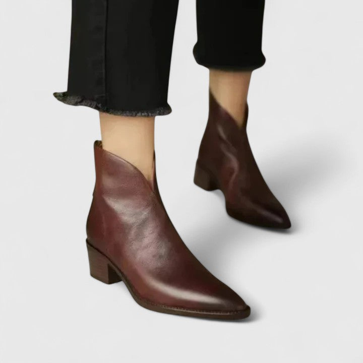 Woman wearing black elegant boots with tailored trousers on a city footpath.