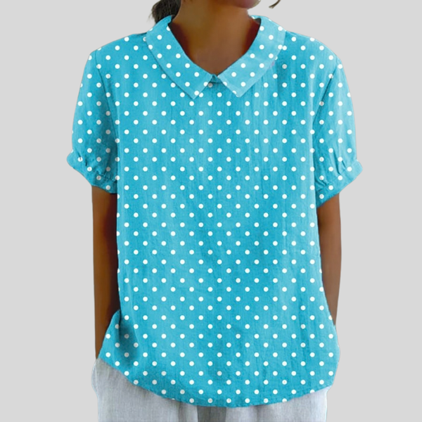 A woman wearing a soft turquoise polka dot top with a structured polo collar, looking feminine and elegant.