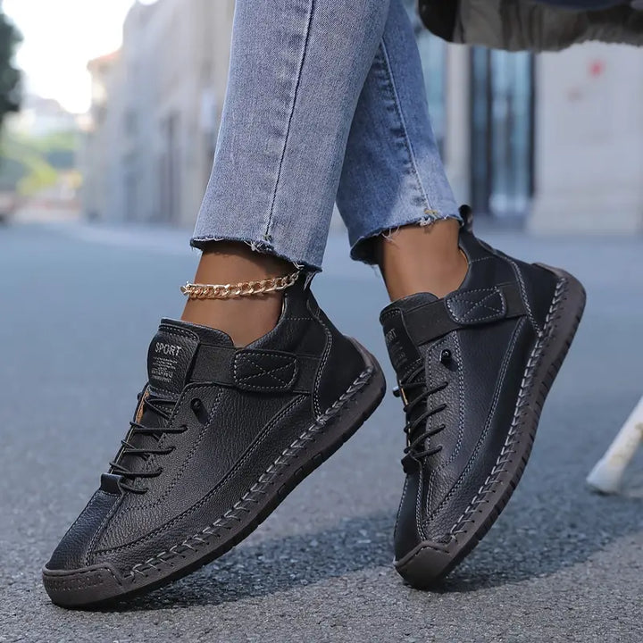 A woman wearing white lace-up orthopaedic trainers with an adjustable strap.