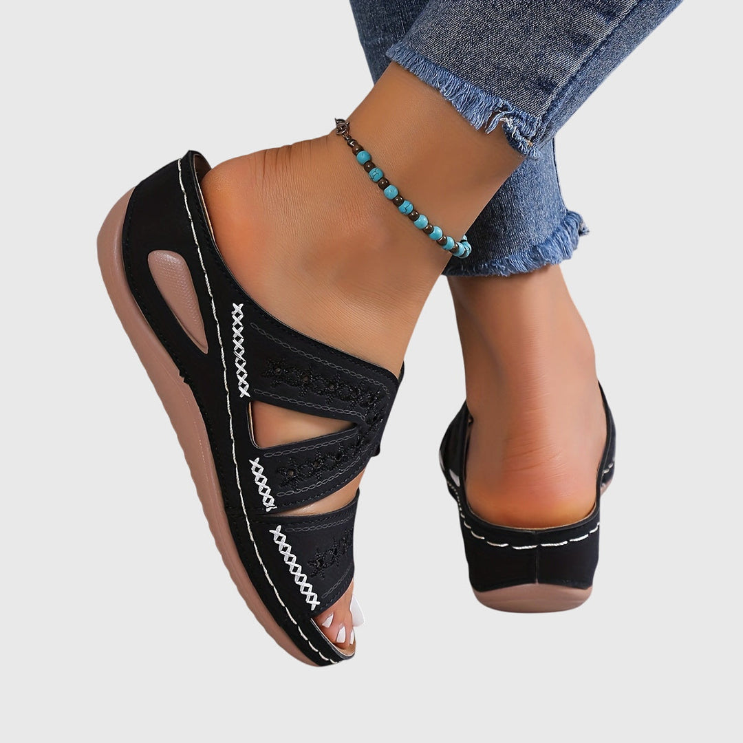 A woman walking gracefully in elegant wide-fit support sandals with an open-front design.