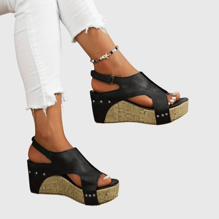 A woman in studded wedge sandals with an open front at a summer event.