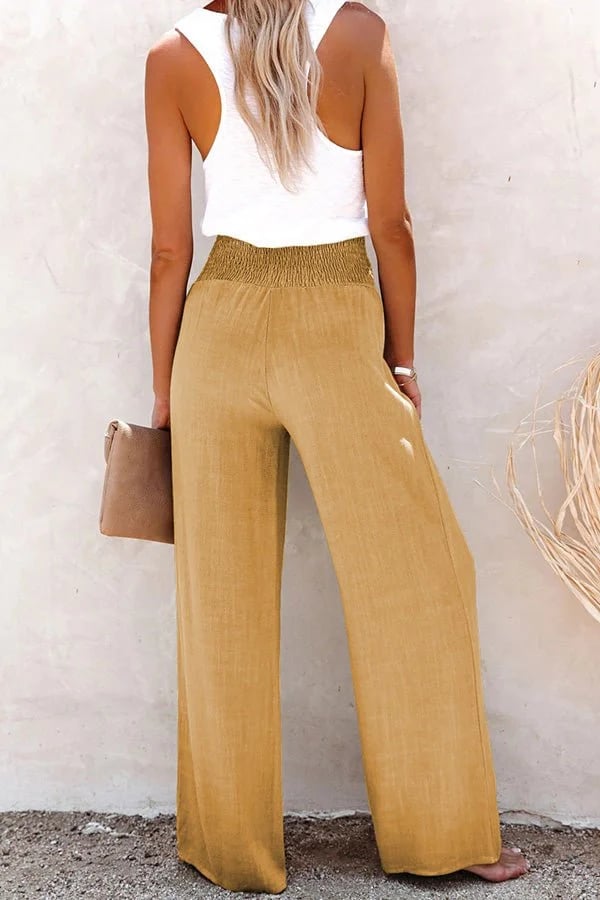 A woman in high-waisted loose wide-leg trousers with subtle button detailing, styled for an elegant everyday look.