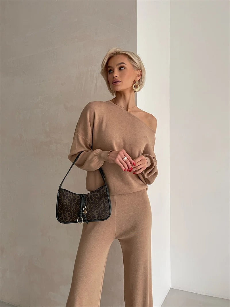 A woman wearing an off-shoulder draped top with wide-leg trousers