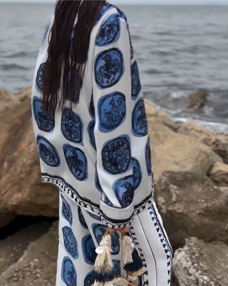 A woman wearing a blue-and-white printed open-collar shirt and matching straight-leg trousers on a warm summer day