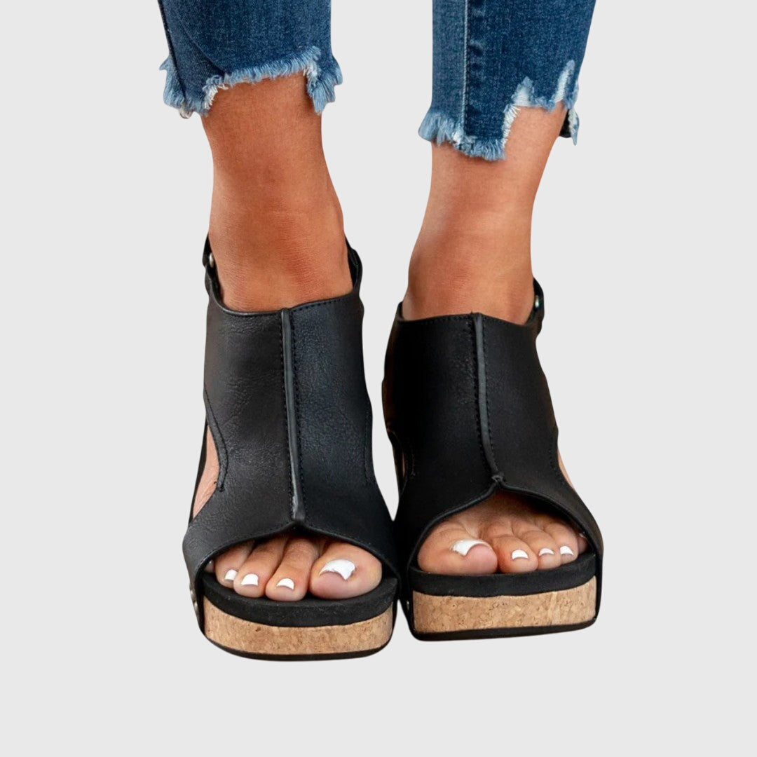 A woman in taupe wedge sandals with an open front, out shopping on a warm day.