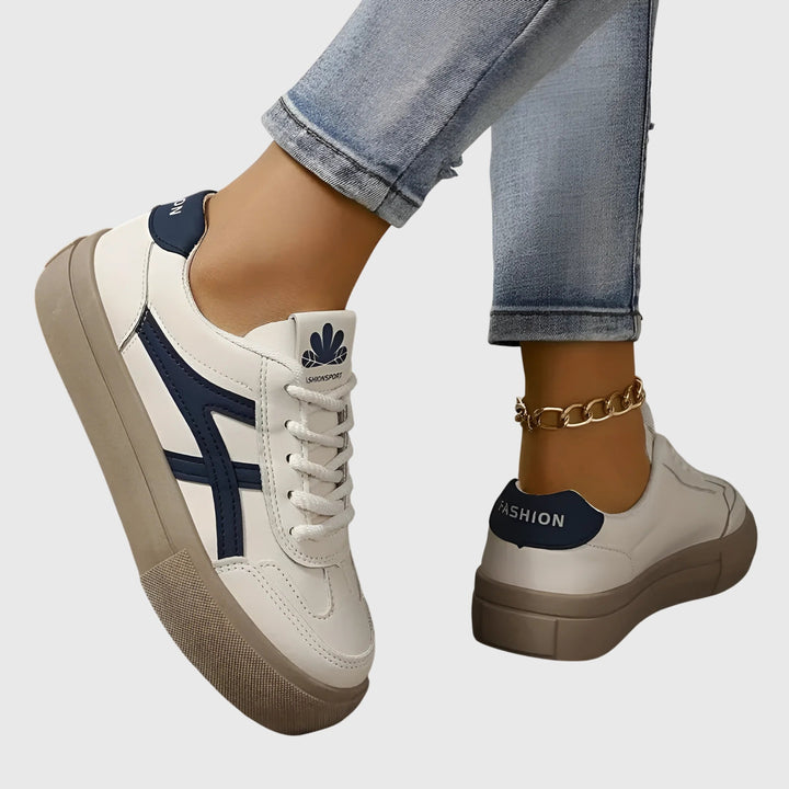 A woman standing comfortably in blue orthopaedic support trainers with wide stabilising heels.
