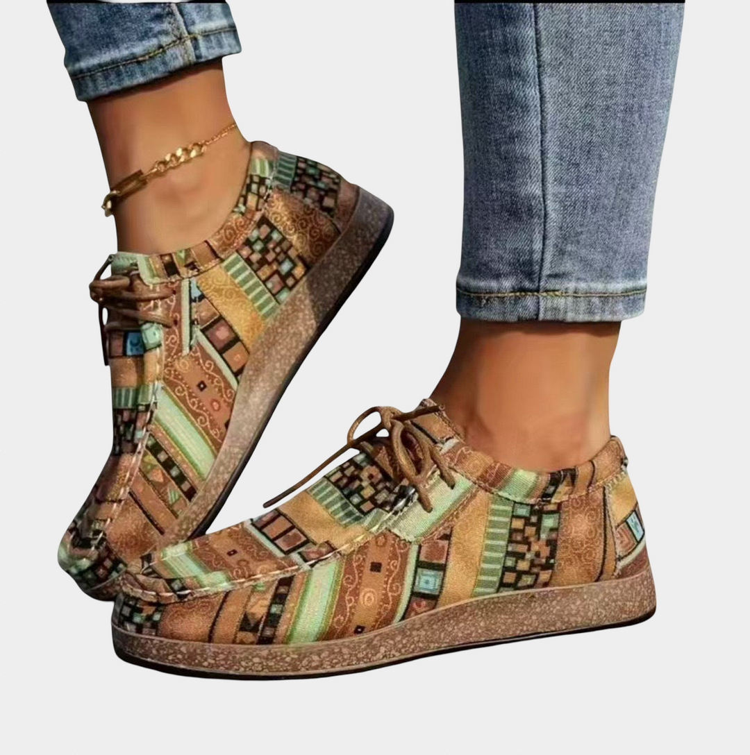 A woman standing in a green boho-print lace-up comfort shoe on a bright day.