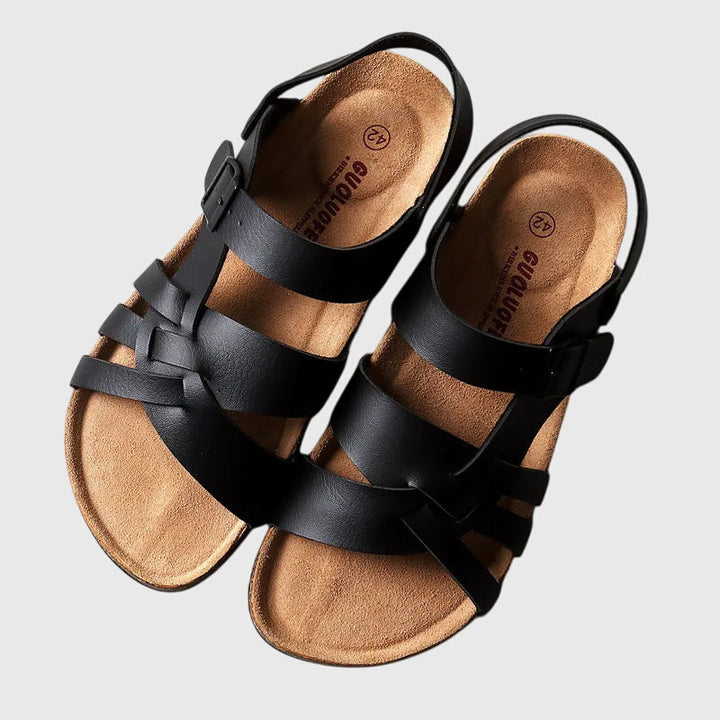 A woman in colourful cross-strap summer sandals with an adjustable ankle buckle on a warm day.