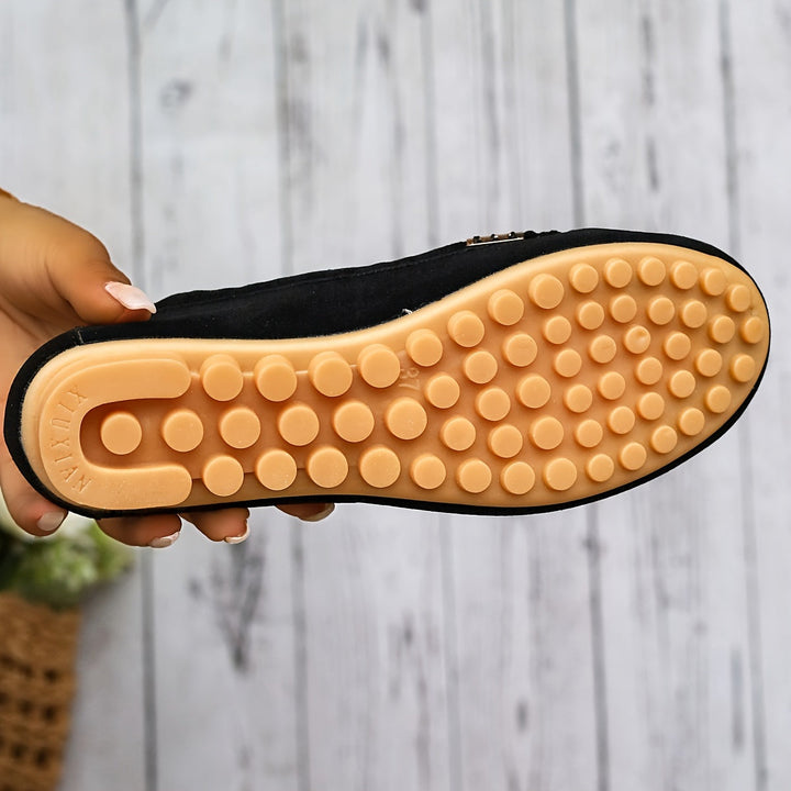 A woman in a ballet-flat loafer stepping lightly along a bright pavement.