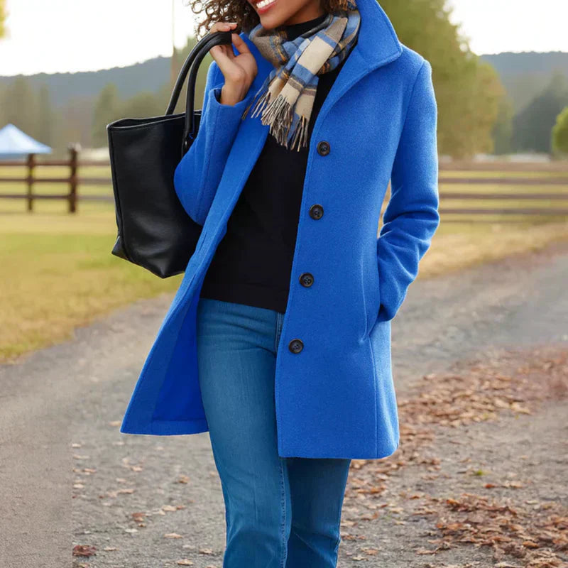 A woman wearing an elegant single-button coat over a jumper on a crisp autumn day.