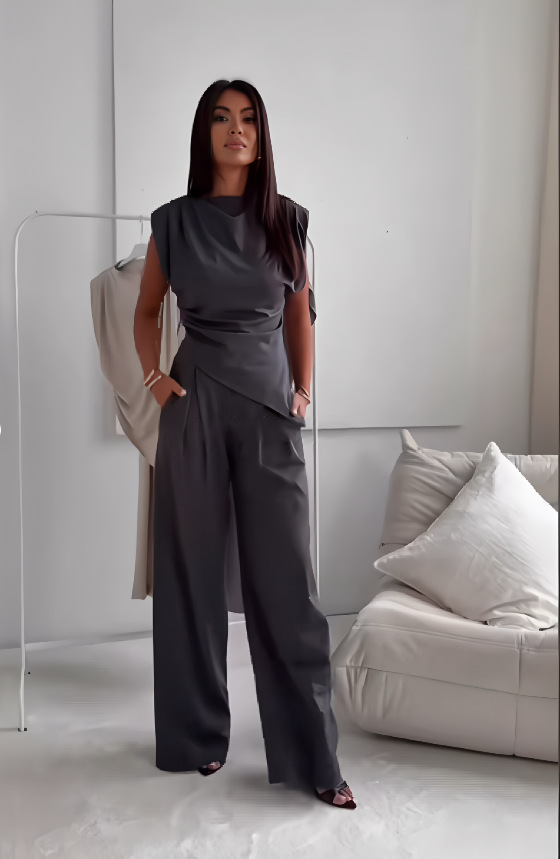 A woman wearing an asymmetric draped top with matching flowing wide trousers.