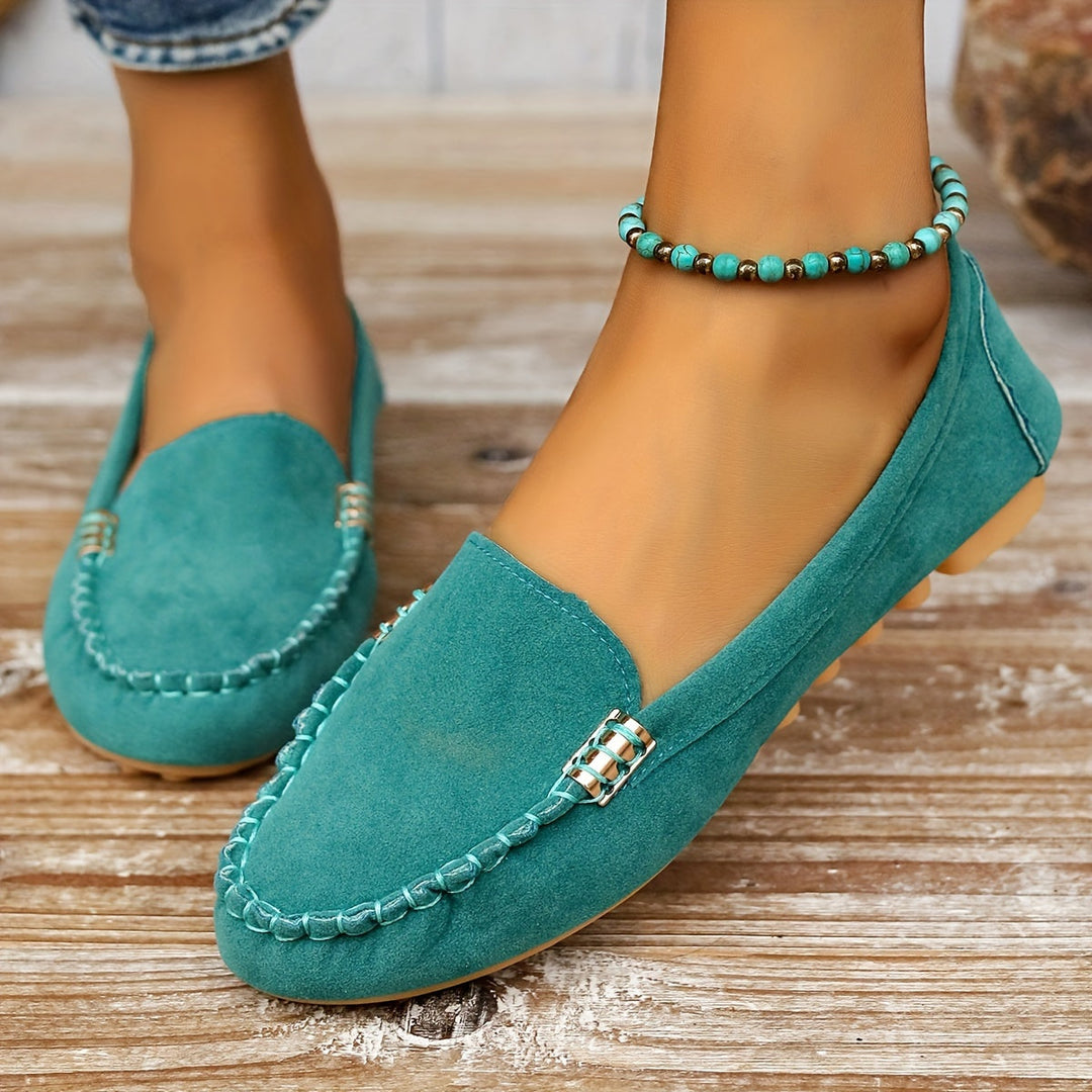 A woman in a ballet-flat loafer stepping lightly along a bright pavement.