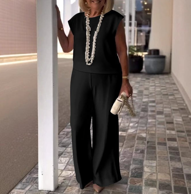 A woman wearing a flowing short-sleeve top with graceful wide-leg trousers.