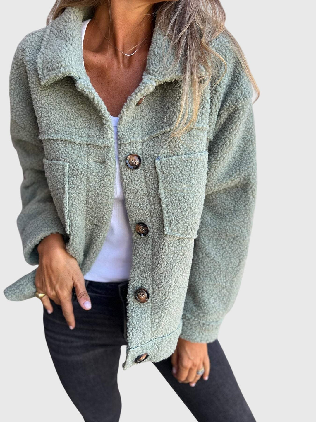A woman wearing an elegant jacket with a button front over a simple outfit, looking polished.