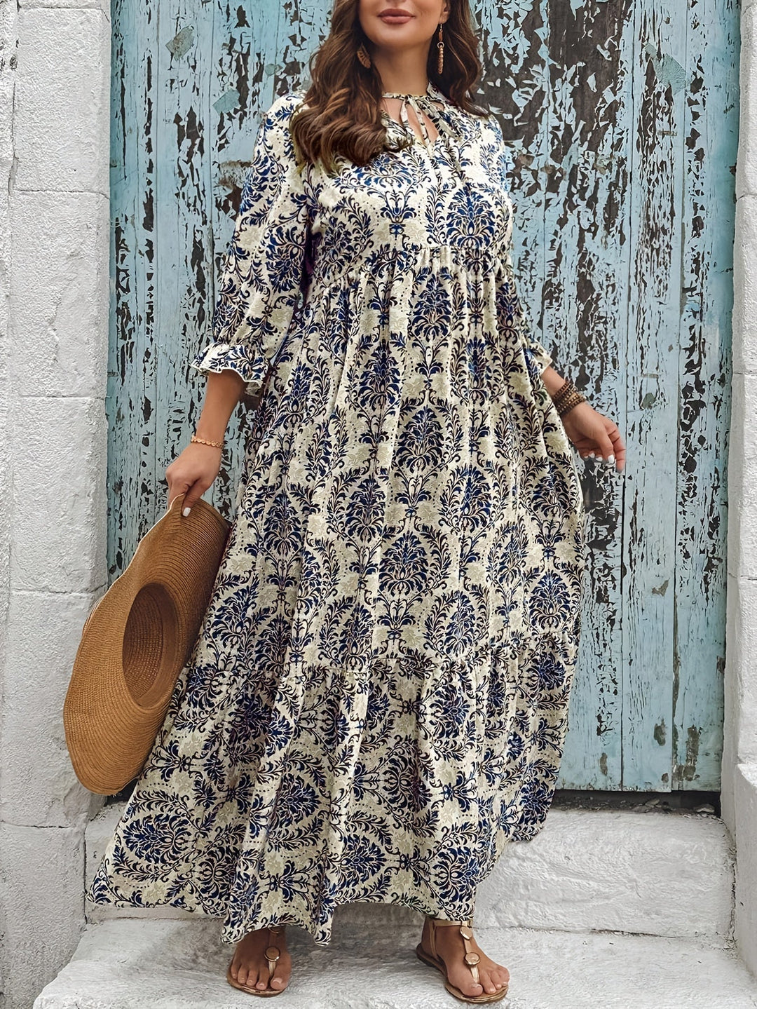Woman strolling by the sea in the Harriet mosaic print maxi dress with a keyhole neckline and bow detail.