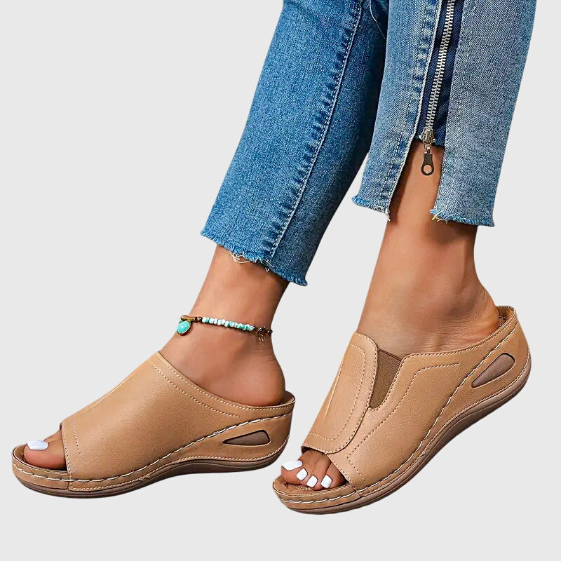 A woman walking confidently in charcoal ergonomic comfort sandals with a broad, cushioned sole.