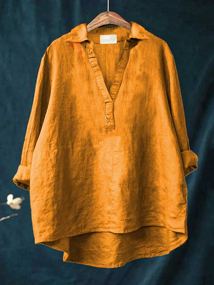 A woman wearing an elegant solid-colour summer blouse with an open V-neck, looking fresh and stylish on a warm day.