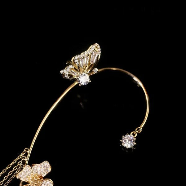 Gold celestial arc earring with a butterfly detail, framing the ear with sparkling luminosity