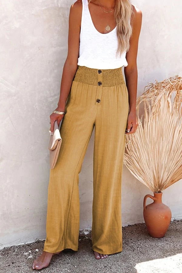 A woman in high-waisted loose wide-leg trousers with subtle button detailing, styled for an elegant everyday look.