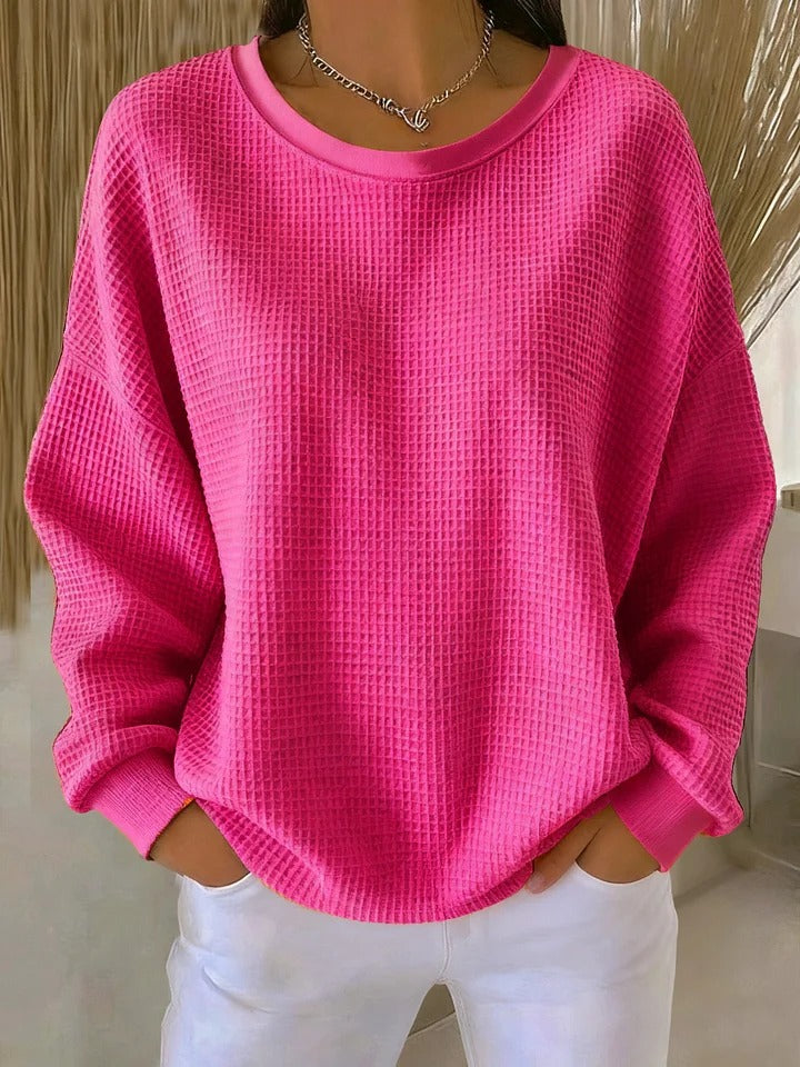 A woman wearing a relaxed-fit waffle-stitch jumper in soft pink with a textured surface