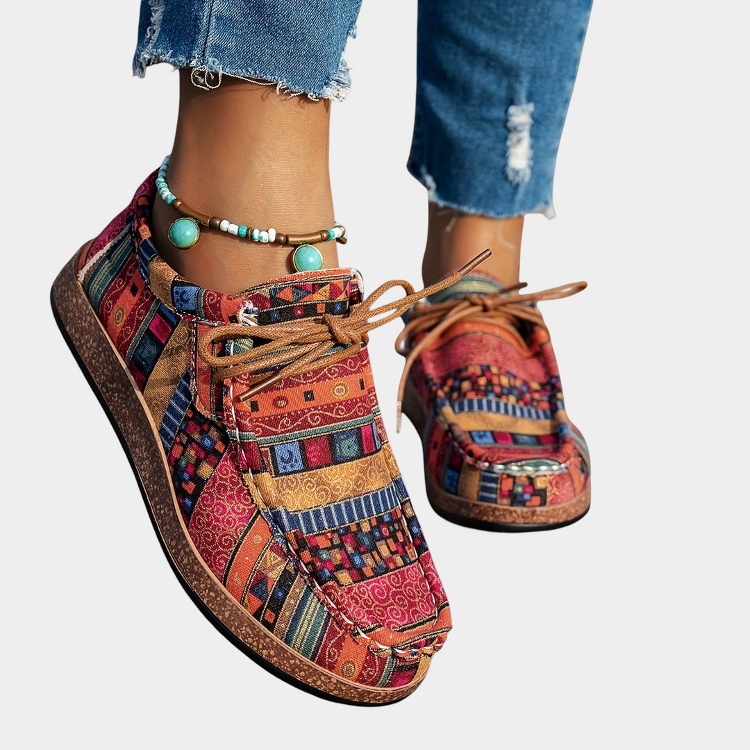 A woman wearing red boho-patterned lightweight trainers on a walk in town.