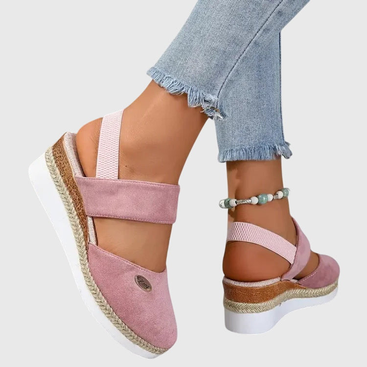 Black closed-toe wedge espadrilles with a wide stretch strap and a braided-trim platform wedge.