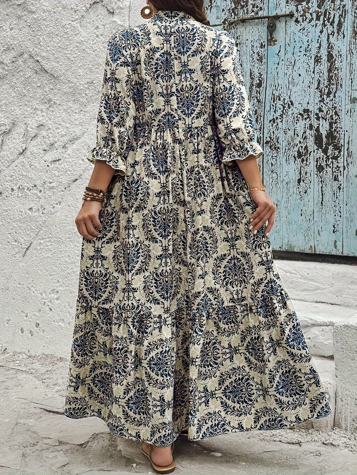 Woman strolling by the sea in the Harriet mosaic print maxi dress with a keyhole neckline and bow detail.