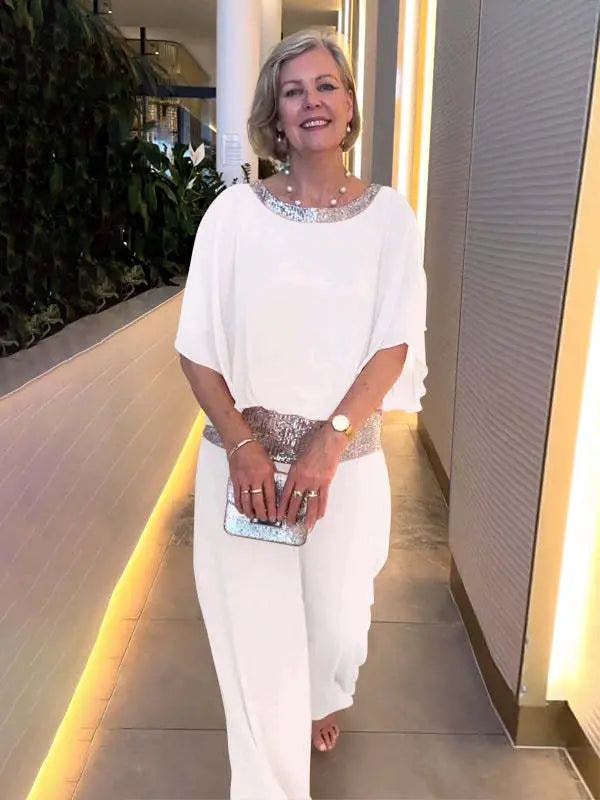 A woman wearing an embellished blouse-style top with softly flowing wide evening trousers.