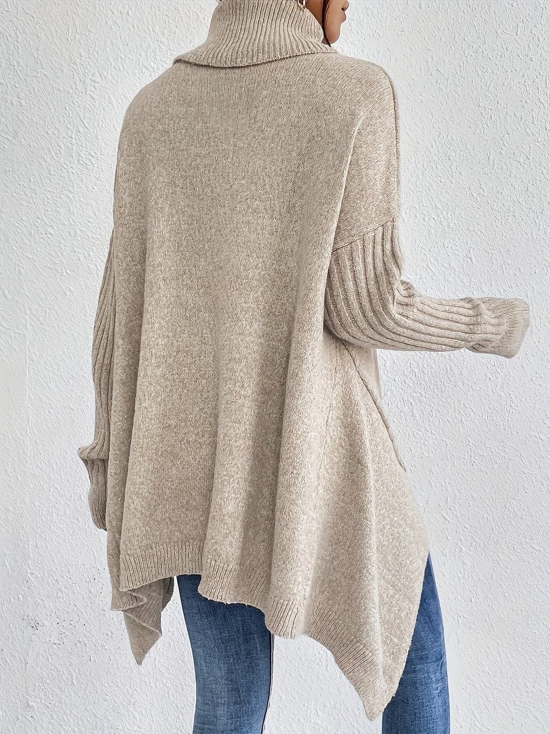 A woman wearing a stand-collar jumper with a chic asymmetric drape, warm and polished.