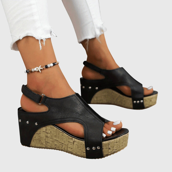 A woman in studded wedge sandals with an open front at a summer event.